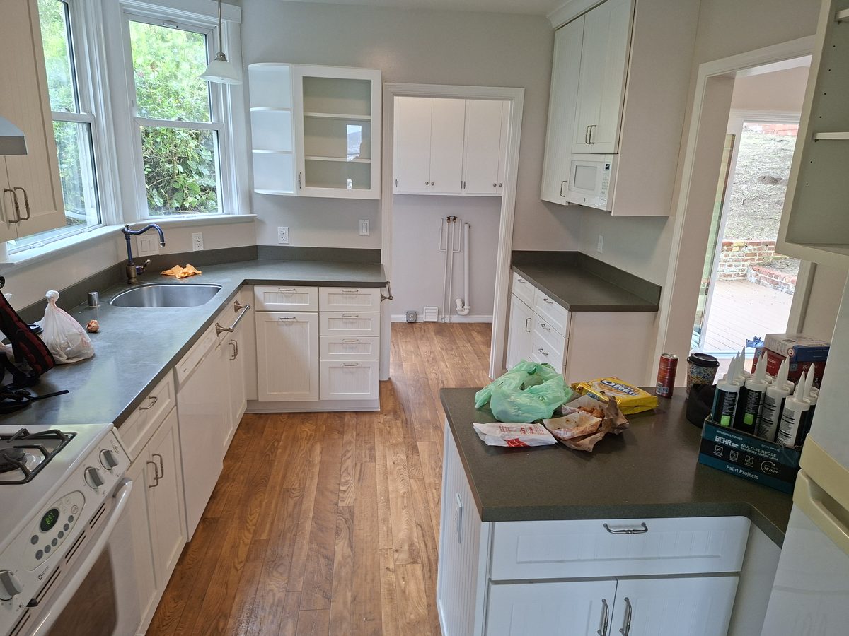 Updated galley kitchen in a Richmond District home with white cabinets and hardwood floors