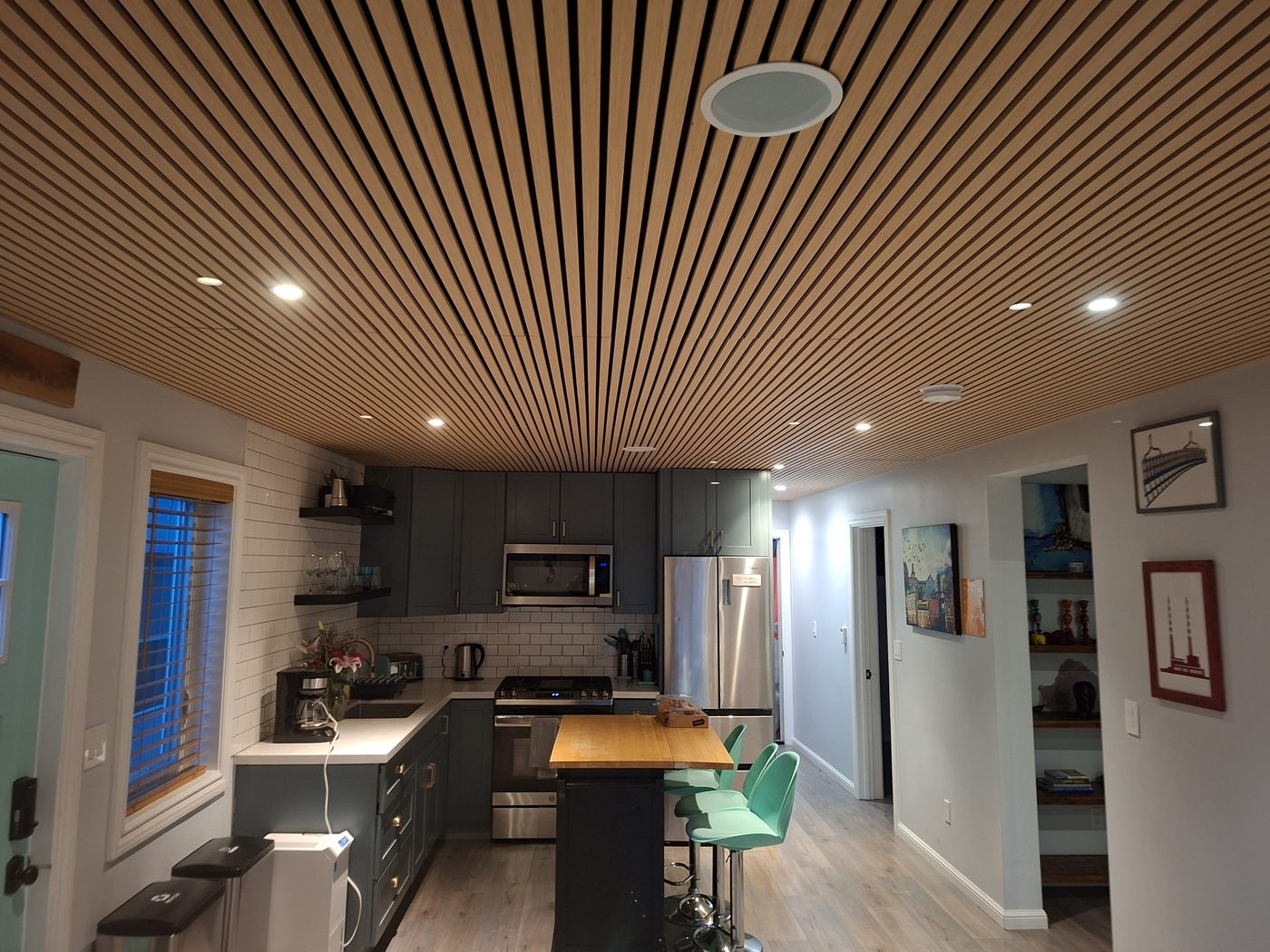 Modern kitchen remodel with dark cabinetry, quartz counters, custom wood slat ceiling, and pendant lighting